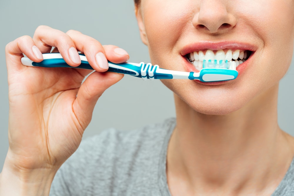 Woman,With,Healthy,White,Teeth,Holds,A,Toothbrush,And,Smiles.