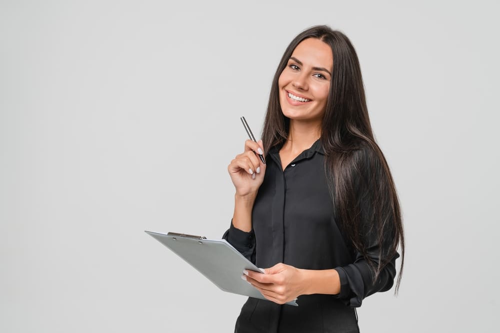 Smiling,Confident,Caucasian,Young,Businesswoman,Auditor,Writing,On,Clipboard,,Signing