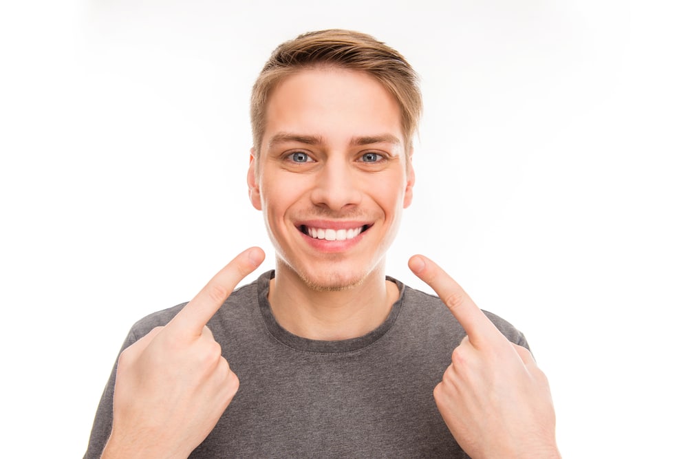 Smilling,Handsome,Man,Gesturing,And,Pointing,On,His,Teeth